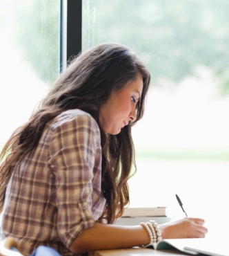 Woman writing in notebook by window